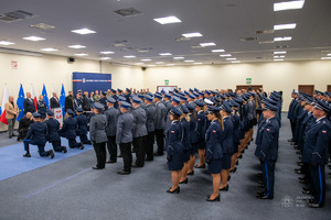 Policjanci w rzędach stoją na sali w galowych mundurach.