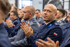 Policjanci siedzą na krzesłach, policjant klaszcze.