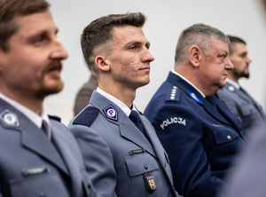 Policjanci siedzą na gali na krzesłach.