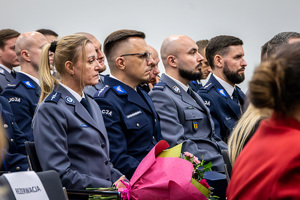 Wyróżnieni policjanci siedzą na krzesłach.