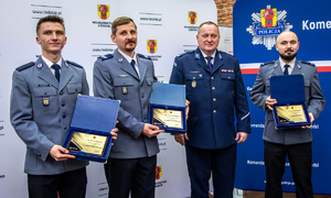 Na ściance stoją wyróżnieni policjanci.