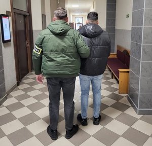 Policjant prowadzi zatrzymanego.