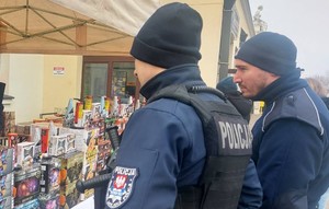 Policjanci stoją przy stoisku z fajerwerkami.