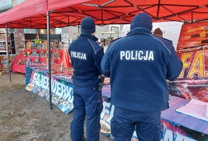 Policjanci stoją przy stoisku z fajerwerkami.