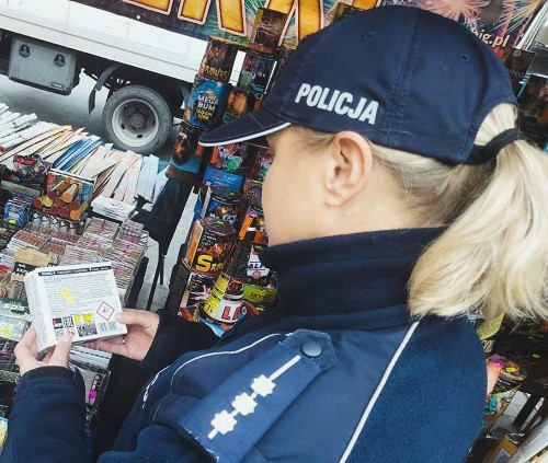 Policjantka trzyma w reku opakowanie z fajerwerkami.