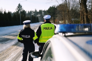 Policjanci stoją przy radiowozie.