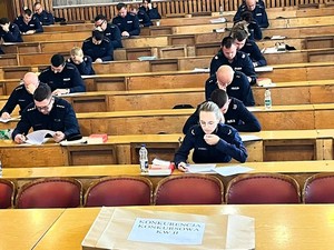 Policjanci siedzą na sali i piszą test.