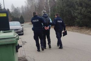 Umundurowani policjanci prowadzą zatrzymanego.