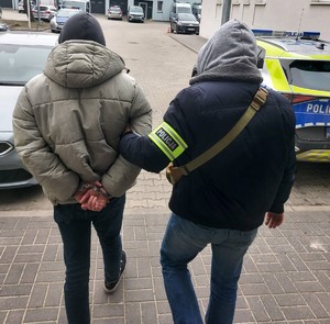 Policjant w cywilu stoi z zatrzymanym.