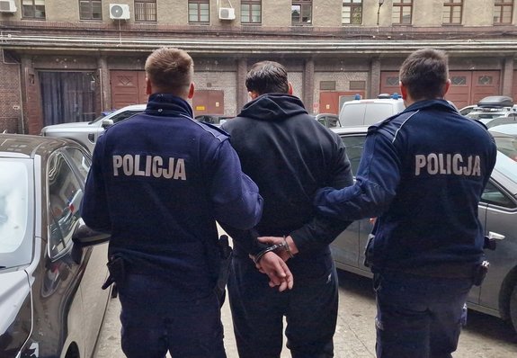 Policjanci stoją z zatrzymanym.