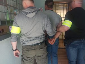 Policjanci stoją z zatrzymanym mężczyzną.