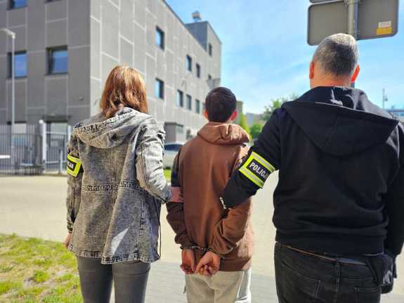 Policjanci stoją z zatrzymanym.