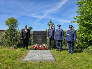 Tablica pamiątkowa, obok stoją mężczyźni i policjanci.