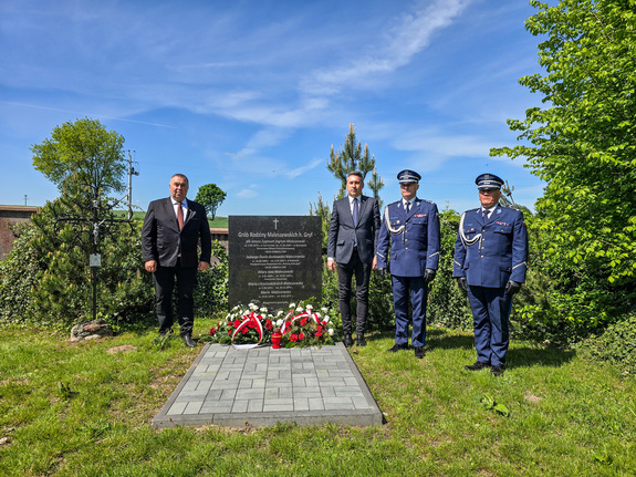 Tablica pamiątkowa, obok stoją mężczyźni i policjanci.