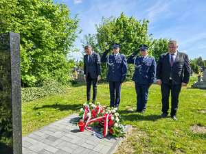 Policjanci i mężczyźni stoją przed tablicą pamiątkową.