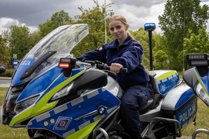 uczennica klasy mundurowej siedzi na policyjnym motocyklu podczas targów pracy.