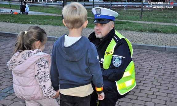 Policjant klęka przed dwójką dzieci.