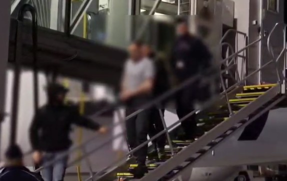 policjanci prowadzą zatrzymanego.