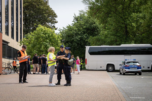 Parking przed uniwersytetem, policjanci rozmawiają z obywatelami.