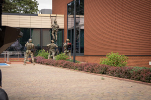 Kontrterroryści wchodzą na dach po drabinie.