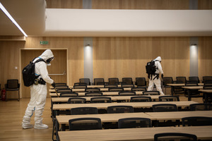 Policjanci z grupy minersko-pirotechnicznej sprawdzają aule, ubrani są  białe kombinezony.