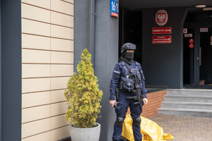 Policjant w pełnym umundurowaniu przed wejściem do uniwersytetu.