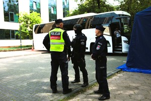 Policjanci stoją na chodniku i rozmawiają.