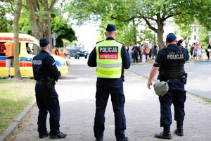 Policjanci stoją na chodniku i rozmawiają.