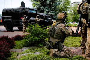 Policjanci kotrterroryści stoją w gotowości, przy turze stoją kolejni kontrterroryści.