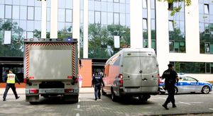 Dwa samochody na parkingu, policjanci biegający obok, radiowóz policyjny.