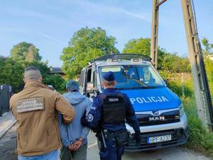 Funkcjonariusz Straży Granicznej i policjant prowadzą zatrzymanego.