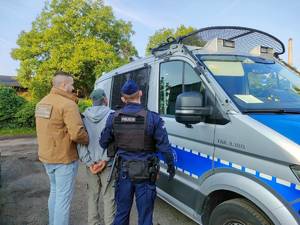 Funkcjonariusz Straży Granicznej i policjant prowadzą zatrzymanego.