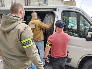 Funkcjonariusz Straży Granicznej i policjant prowadzą zatrzymanego.