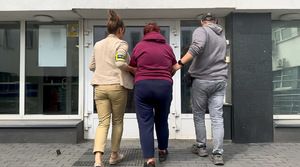 Policjanci prowadzą zatrzymaną na dziedzińcu.
