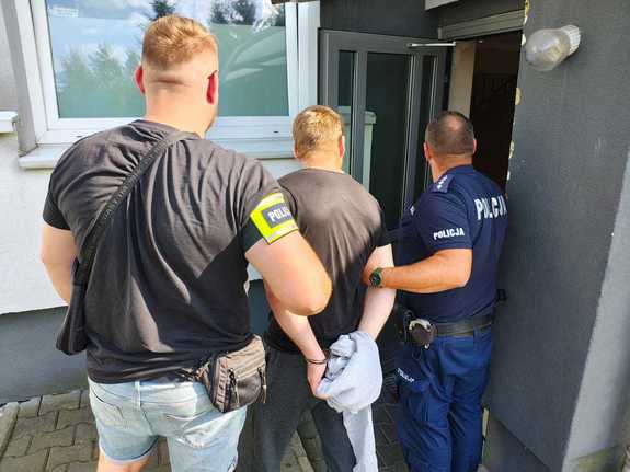 Policjanci prowadzą zatrzymanego mężczyznę.