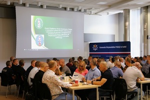 Prezentacja na ekranie, na krzesłach siedzą policjanci.