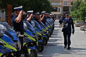 Komendant Wojewódzki policji w Łodzi maszeruje przed szpalerem policyjnych motocyklistów.