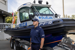 Policjant przy łodzi motorowej.