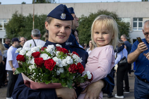 Policjantka z kwiatami i dzieckiem na ręku.