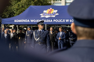 Dowódca uroczystości, za nim zaproszeni goście pod namiotem.