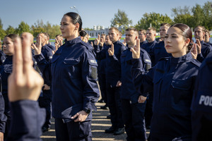 Nowo przyjęci policjanci składają ślubowanie maja podniesione dwa palce prawej ręki.