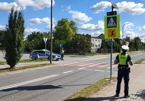 Policjanci z ruchu drogowego stoją w okolicy przejścia dla pieszych.