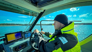 Policjant kieruje łodzią policyjną.