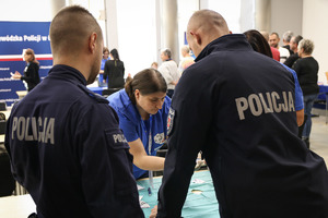Dwóch policjantów stoi tyłem i czeka na badanie.