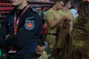 Policjant na tle strażaków.