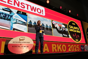 Policjantka na scenie mówi do mikrofonu.