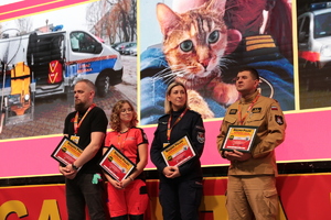 Policjantka stojąca obok funkcjonariuszy innych służb na scenie.