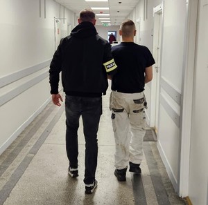 Policjant z zatrzymanym na korytarzu.