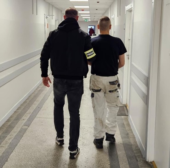 Policjant z zatrzymanym na korytarzu.