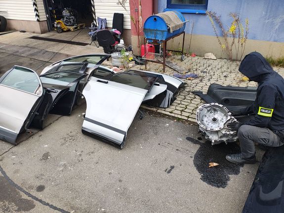 Policjant przegląda zabezpieczone części samochodowe.